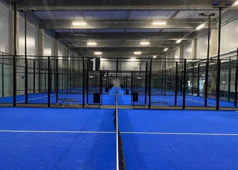 Sininen padelkenttä verkkojen yli katsottuna